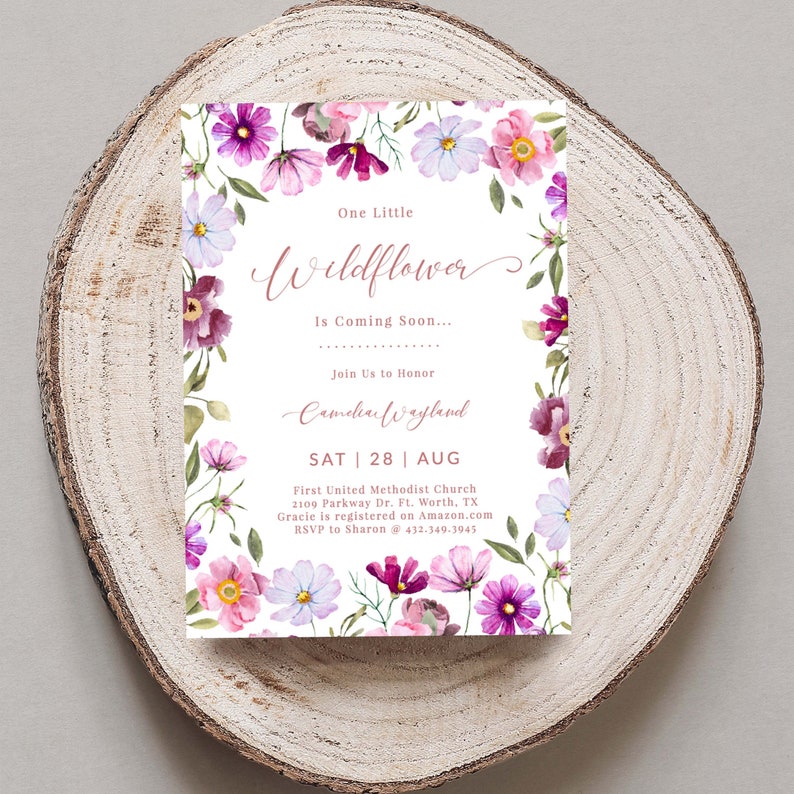 Pu&ograve; includere: Un invito a una festa di baby shower floreale con un design ad acquerello rosa e viola. L'invito recita "One Little Wildflower is Coming Soon..." e include il nome del bambino, la data e la posizione dell'evento.