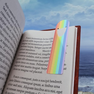 May include: A rainbow-colored bookmark with a smiling face cutout. The bookmark is made of metal and has a shiny finish.