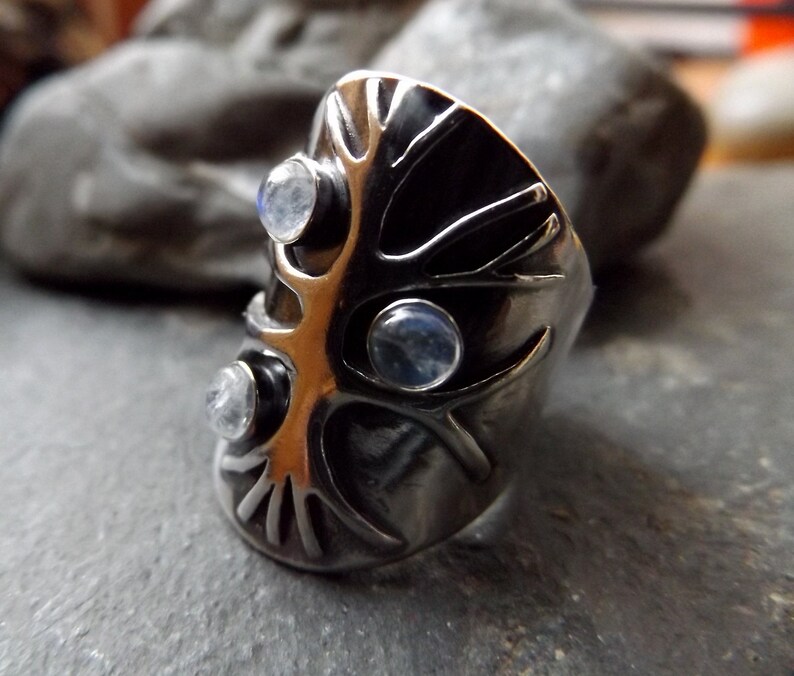 May include: A silver ring with a tree design and three moonstone gems.