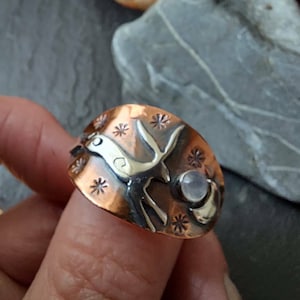 Op de afbeelding: Een koperen ring met een zilveren hertontwerp en een accent van maansteen. De ring is versierd met kleine sterren.
