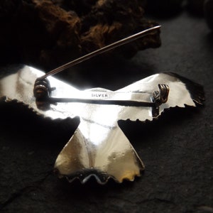 May include: Silver eagle brooch with a detailed design and a pin closure. The back of the brooch is marked "SILVER".