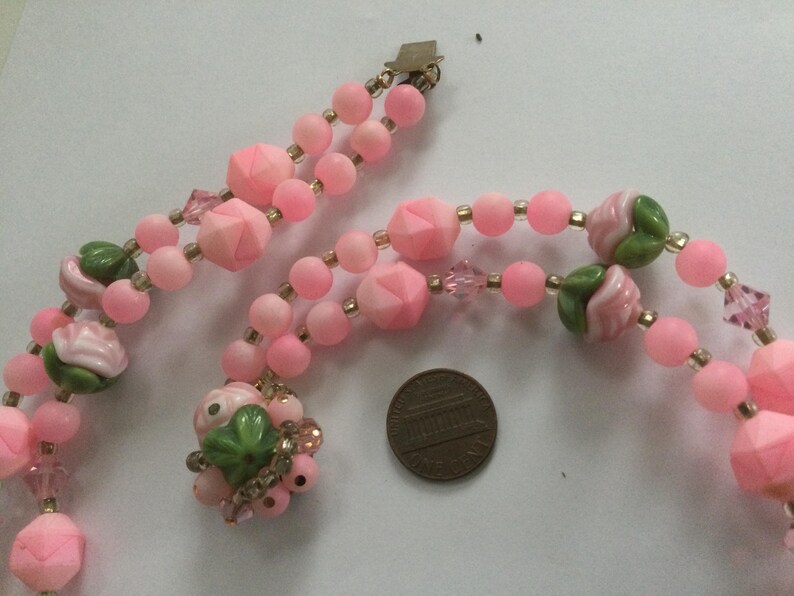 May include: A pink and green glass bead necklace with rose-shaped beads and a gold clasp.