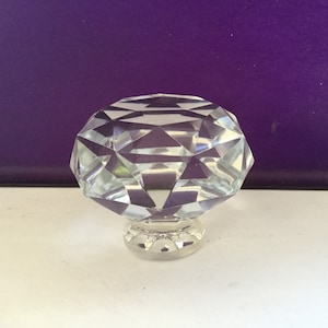 May include: A clear crystal diamond-shaped cabinet knob with a silver base.