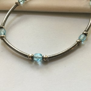 May include: A silver bracelet with light blue beads.