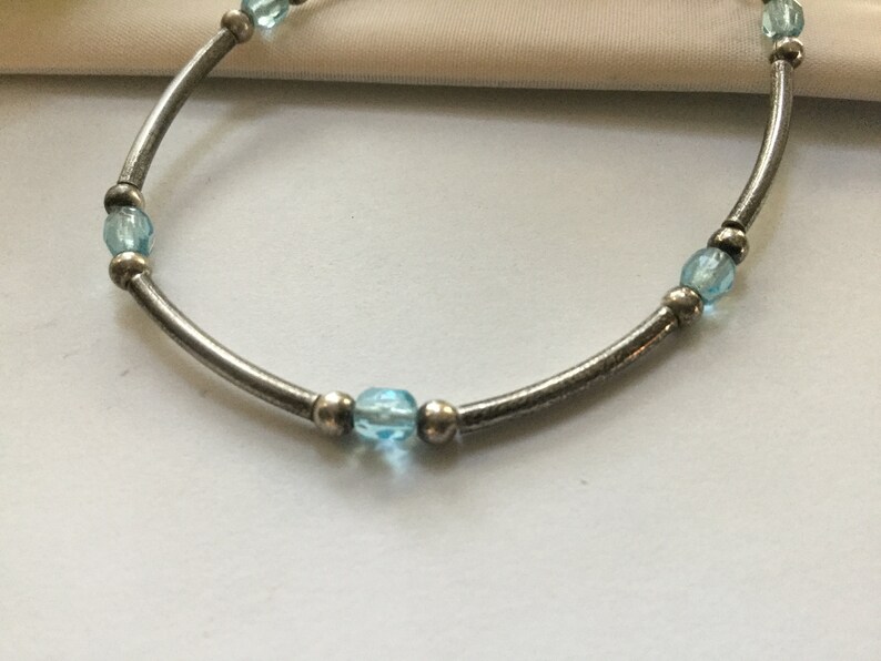 May include: A silver bracelet with light blue beads.