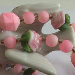 May include: A pink and green beaded necklace with flower-shaped beads and crystal accents.