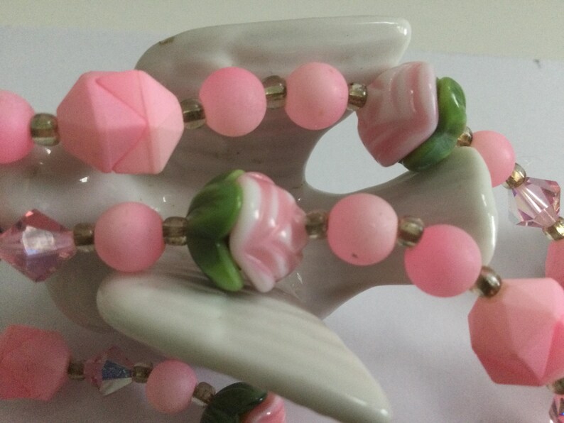 May include: A pink and green beaded necklace with flower-shaped beads and crystal accents.