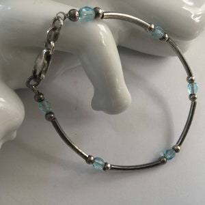 May include: A silver bracelet with a delicate chain and light blue beads.