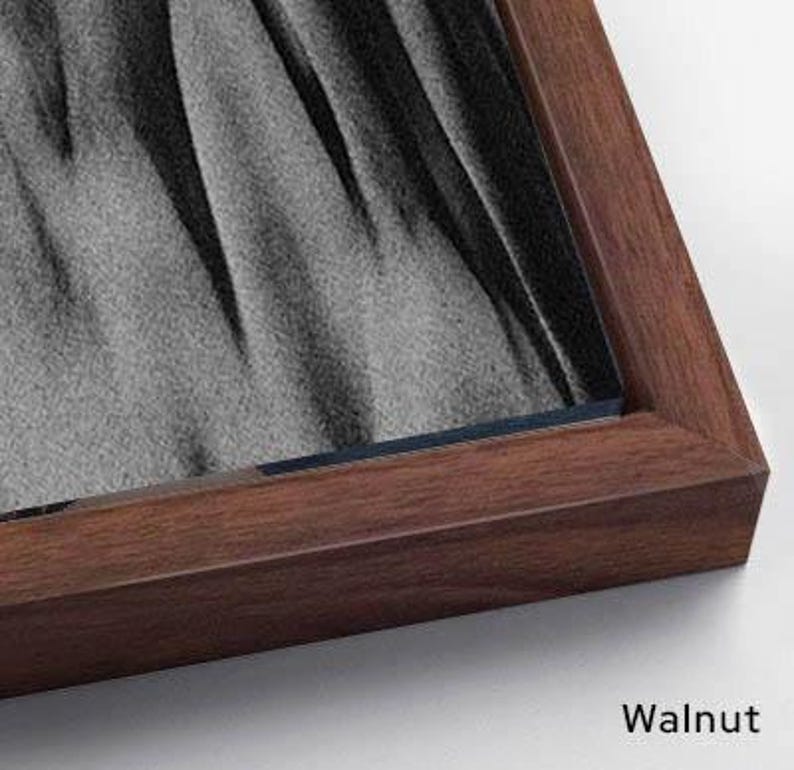 Puede incluir: Una obra de arte enmarcada con acabado de nogal. El marco rodea una obra de arte con tonos grises y negros. La palabra "Walnut" est&aacute; impresa en la esquina inferior derecha.