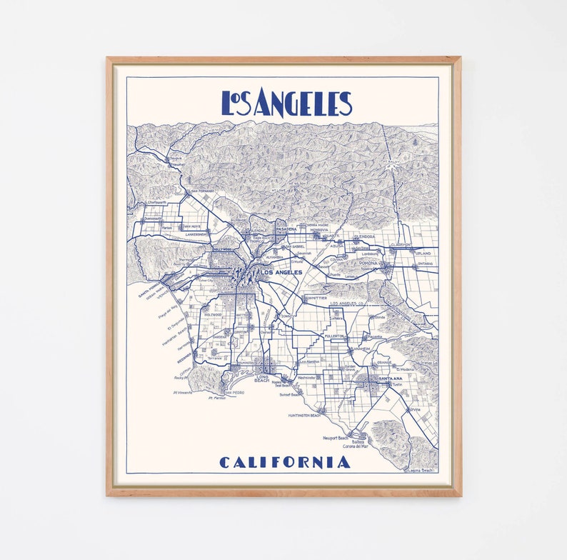 Pu&ograve; includere: Una mappa in stile vintage di Los Angeles, California, stampata in inchiostro blu su sfondo bianco. La mappa mostra le principali strade e quartieri della citt&agrave;, tra cui Hollywood, Beverly Hills e il centro di Los Angeles.