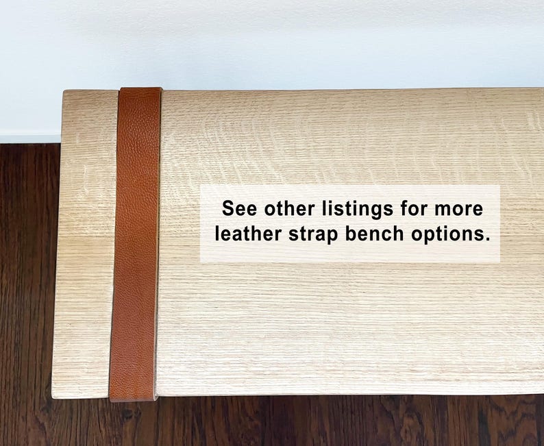 May include: A light-colored wooden bench with a brown leather strap detail. The bench has a rectangular shape and is made of light-colored wood. The leather strap is vertically placed on the side of the bench. Text on the bench reads: See other listings for more leather strap bench options.