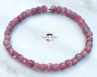 May include: A pink gemstone bracelet with a silver bead accent. The bracelet is made of small, faceted beads and is strung on elastic.