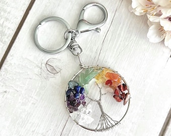 May include: A silver tree of life keychain with a rainbow of gemstones. The keychain features a silver ring with a silver chain attached to a silver split ring.