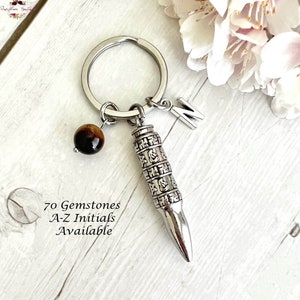 May include: Silver bullet keychain with a tiger's eye bead and a letter 'N' charm. The bullet is engraved with a pattern of symbols. The text '70 Gemstones A-Z Initials Available' is visible below the keychain.
