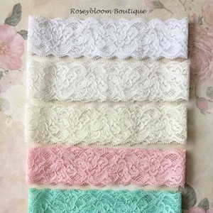 May include: Six different colours of lace trim, including white, ivory, pink, mint green, and black. The lace trim is delicate and has a floral pattern.