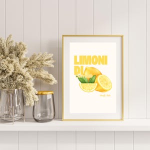 May include: A gold framed print with a white background and the text "LIMONI DI" in yellow. The print features a watercolor illustration of lemons.