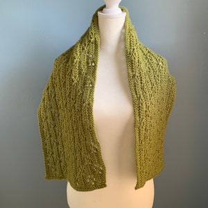 May include: A green crocheted scarf with a lacy pattern, displayed on a white mannequin.