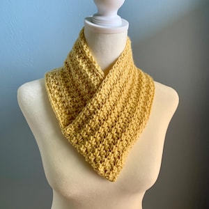 May include: A yellow crocheted infinity scarf on a white mannequin.