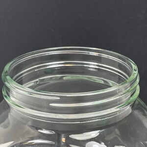 May include: A clear glass jar with a wide mouth and a rounded body. The rim of the jar has a series of concentric rings. The jar is designed for storage and is suitable for various uses.