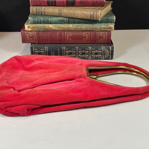 May include: A red velvet handbag with a gold metal frame handle.