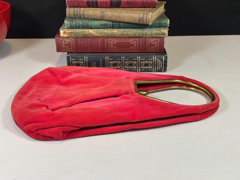May include: A red velvet handbag with a gold metal frame handle.