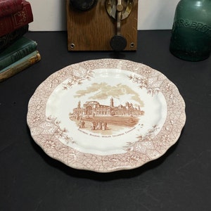 Puede incluir: Un plato de cerámica blanco con un borde floral marrón y una imagen marrón del Edificio Eléctrico de la Exposición Colombina Mundial en Chicago, Illinois.