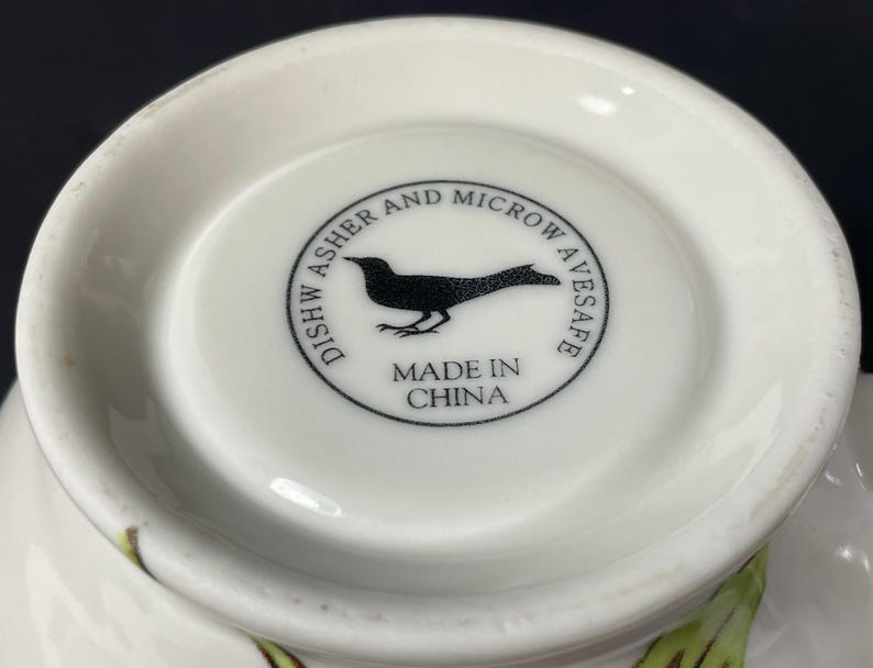 Op de afbeelding: Witte keramische kom met een zwarte vogel afbeelding en de tekst "Dish Washer and Microwave Safe Made in China".