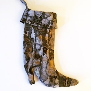 May include: A gray and gold patterned stocking with a pointed toe and a folded-over cuff.