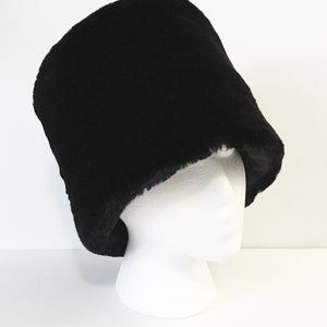 May include: A black fur hat with a wide brim. The hat is made of a soft, plush material and has a classic, timeless design.