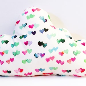 May include: A white cloud-shaped pillow with a pattern of colorful watercolor hearts.