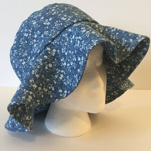 May include: A blue sun hat with a white floral pattern. The hat has a wide brim and is made of a soft, lightweight fabric.