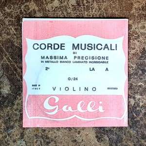 May include: A pink and white package of violin strings labeled "CORDE MUSICALI DI MASSIMA PRECISIONE IN METALLO BANCO LAMINATO INOSSIDABILE 2 LA A 0/24 VIOLINO Galli"