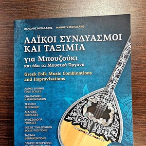 Könnte beinhalten: Ein blaues Buch mit dem Titel "Griechische Folk-Musik-Kombinationen und Improvisationen" für die Bouzouki und andere Musikinstrumente. Der Buchumschlag zeigt eine Bouzouki und den Text "ΛΑΪΚΟΙ ΣΥΝΔΥΑΣΜΟΙ ΚΑΙ ΤΑΞΙΜΙΑ".
