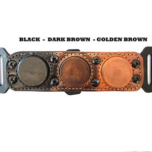 May include: A leather accessory with three circular, magnetic closures in black, dark brown, and golden brown. The text "BLACK - DARK BROWN - GOLDEN BROWN" is above the item. The item has black plastic connectors on each end.