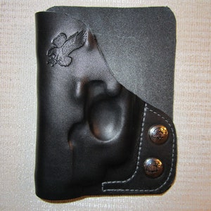 May include: Black leather holster with a flap and two snap closures. The holster has an eagle design embossed on the front.