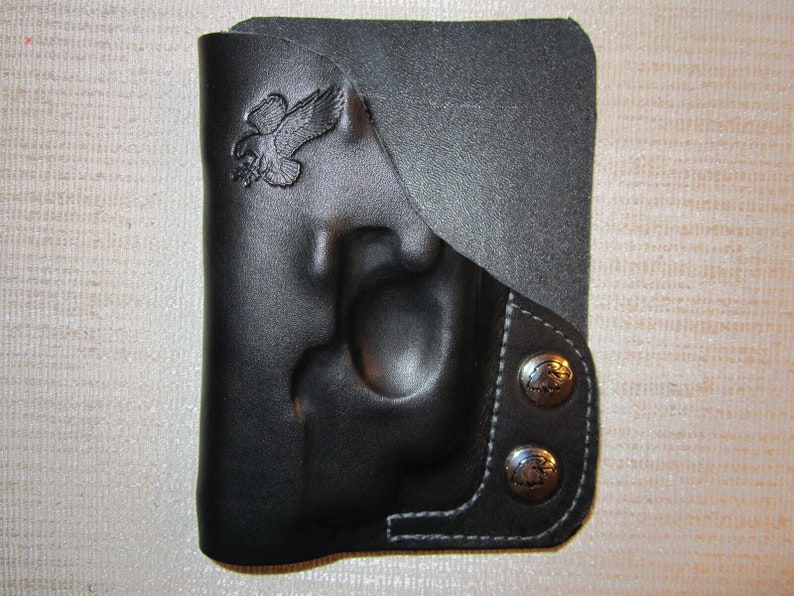 May include: Black leather holster with a flap and two snap closures. The holster has an eagle design embossed on the front.