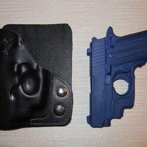 May include: A black leather holster with a snap closure and a blue handgun with a black barrel.