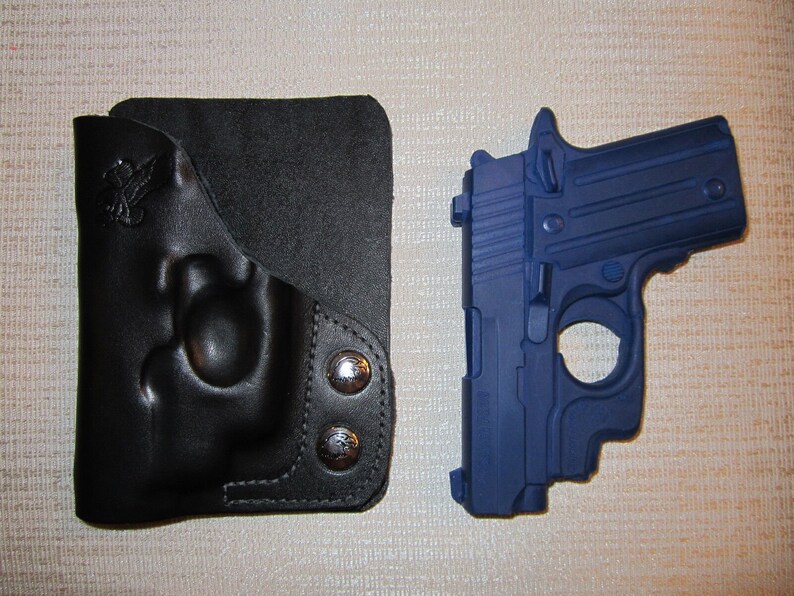 May include: A black leather holster with a snap closure and a blue handgun with a black barrel.
