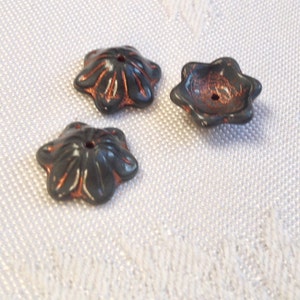 May include: Three black and copper flower-shaped buttons with a raised design.