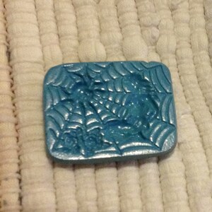 May include: A blue ceramic mold with a spider web design. The mold is textured and has a glossy finish.