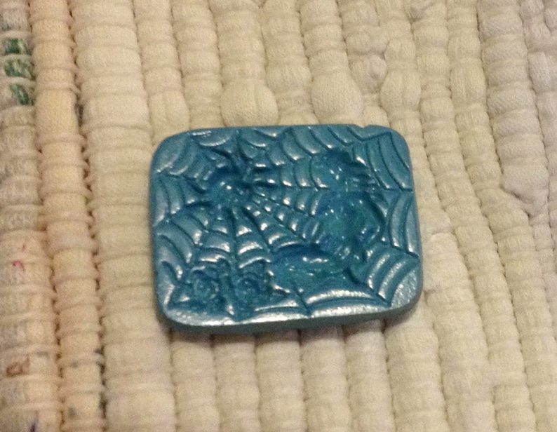 May include: A blue ceramic mold with a spider web design. The mold is textured and has a glossy finish.