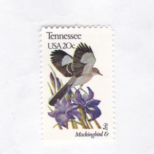 May include: A vintage 20c USA postage stamp featuring a brown and white mockingbird in flight with purple iris flowers. The stamp says "Tennessee" and "USA 20c" and "Mockingbird & Iris".