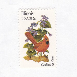 May include: A vintage 20-cent US postage stamp featuring a red cardinal bird perched on a branch with purple violets. The stamp reads "Illinois USA 20c Cardinal & Violet".
