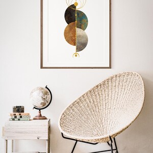 May include: A framed print with a geometric design featuring three overlapping circles in shades of brown, blue, and gray. The circles are surrounded by gold rings and lines.