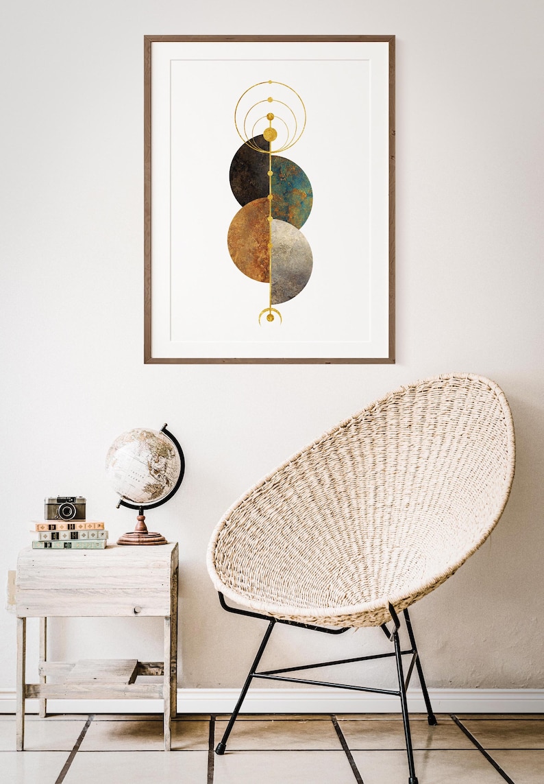 May include: A framed print with a geometric design featuring three overlapping circles in shades of brown, blue, and gray. The circles are surrounded by gold rings and lines.