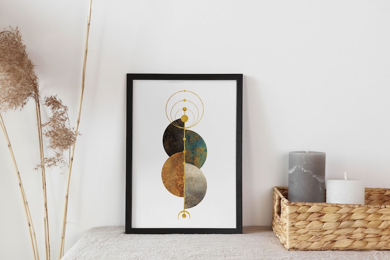 May include: A framed print with a geometric design featuring overlapping circles in shades of brown, blue, and gold. The circles are arranged vertically and are connected by a thin gold line. The background is white.