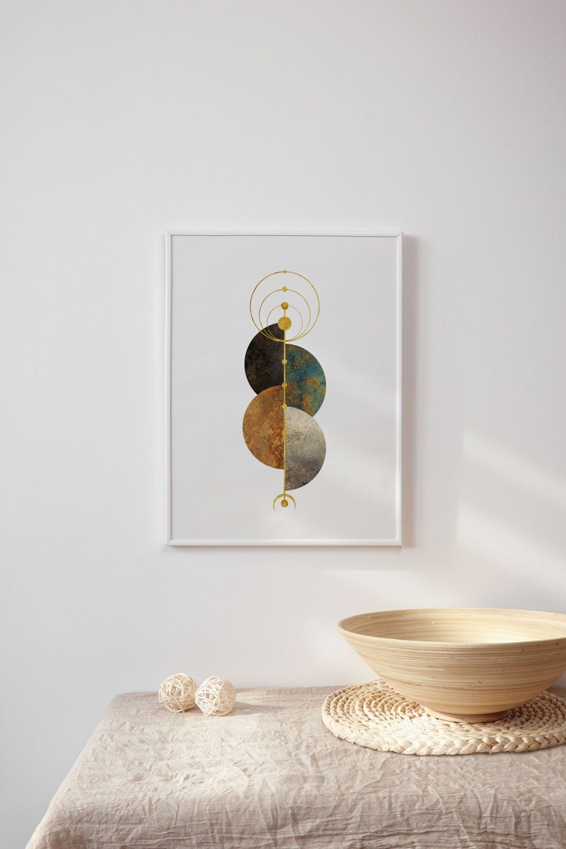 May include: A framed print with a geometric design featuring three overlapping circles in shades of brown, blue, and gray. The circles are arranged vertically and are connected by a thin gold line. The background is white.