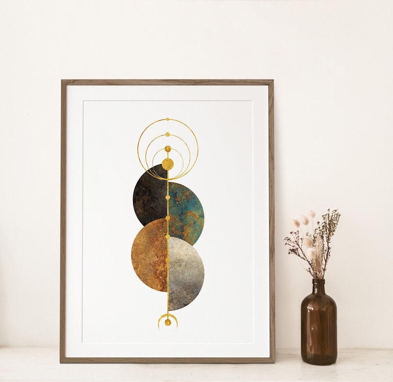 May include: A framed print with a geometric design featuring overlapping circles in shades of brown, blue, and gold. The circles are arranged vertically and are connected by a thin gold line. The background is white.
