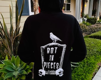 Könnte beinhalten: Schwarzer Kapuzenpullover mit einem weißen Aufdruck eines Grabsteins mit einem Vogel obenauf und dem Text "Rot in Pieces" mit zwei Totenköpfen unten.