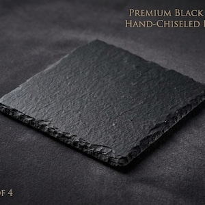 May include: A square, black slate coaster with hand-chiseled edges. The coaster has a textured surface and is set against a dark background. Text on the image reads "Premium Black Slate Hand-Chiseled Edges" and "Set of 4".